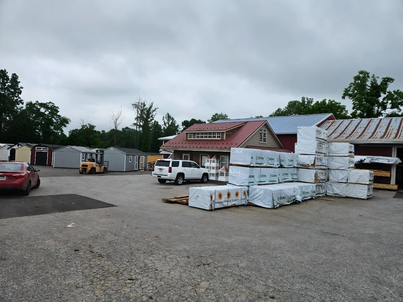 LP SmartSide siding bundles stacked in the yard with finished structures and office building in background