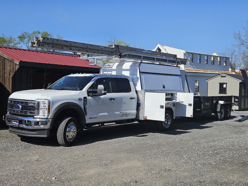 White Pine Structures Ford F-550 crew cab service truck with ladder rack, utility bed, and flatbed trailer at the Parkesburg lot